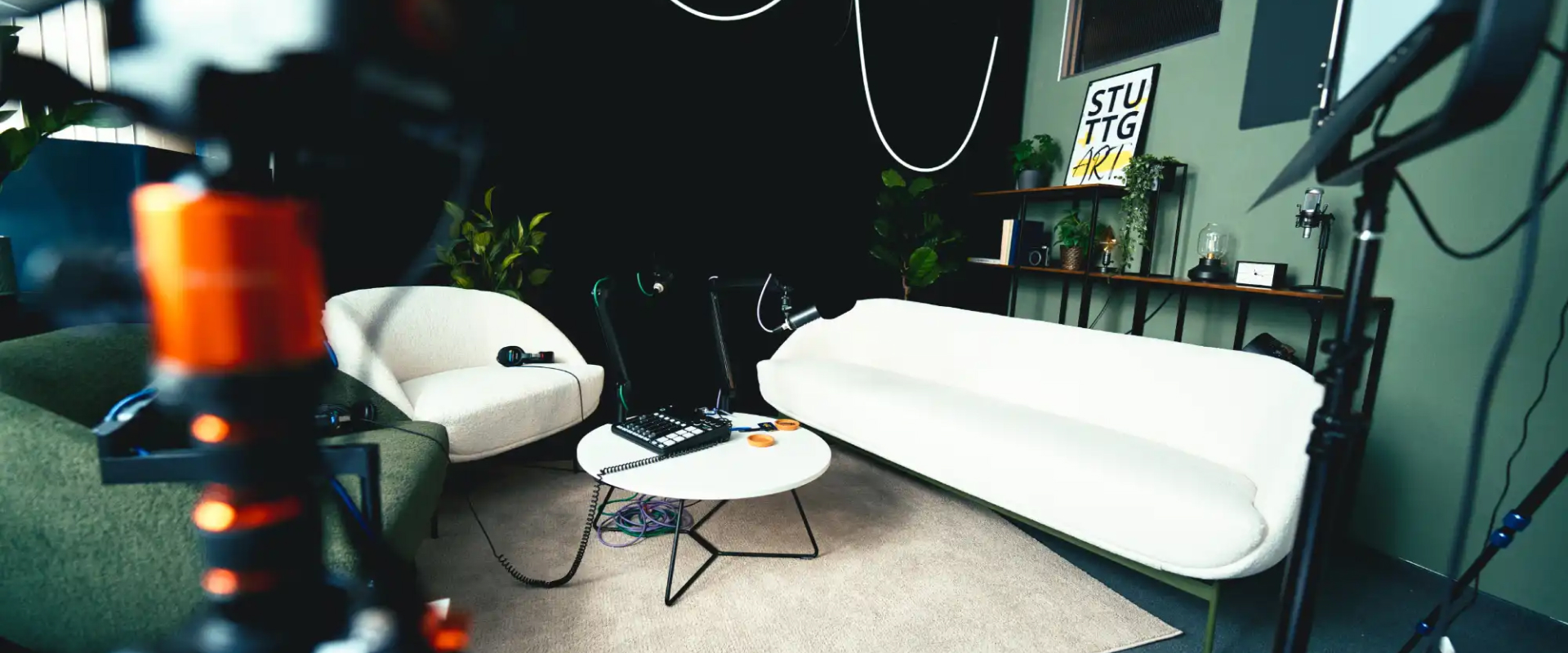 Modernes Podcast-Studio in Stuttgart mit professioneller Audio- und Videotechnik, weißem Sofa und Lounge-Atmosphäre.
